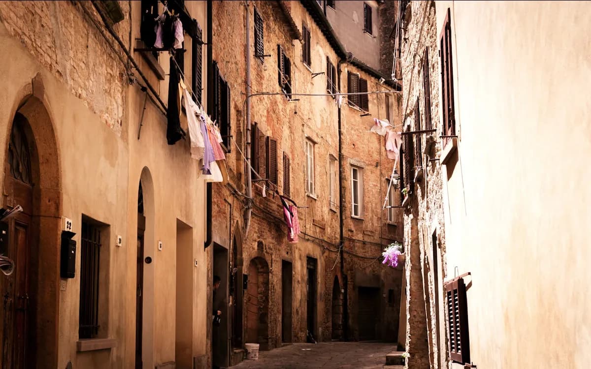 A narrow sunlit alley in an old town, washing strung between the balconies